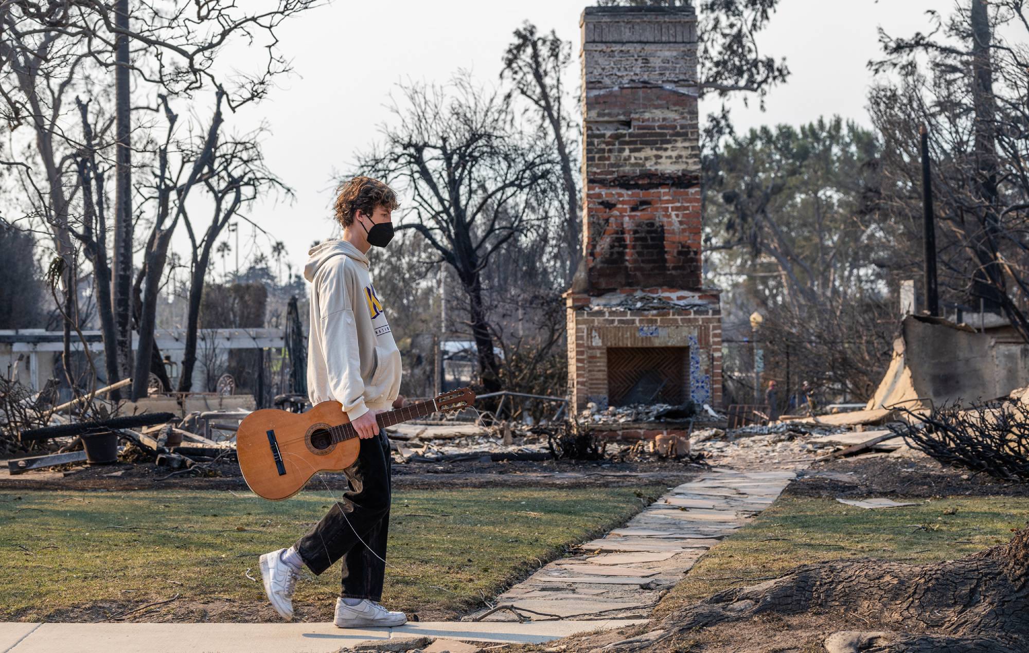 Jet Gross, 17 ans, marche avec une guitare qu'un ami a demandé à trouver à Pacific Palisades, en Californie, le vendredi 10 janvier 2025. (Myung J. Chun / Los Angeles Times via Getty Images)